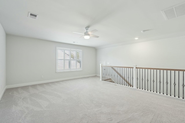 empty room with ceiling fan, carpet floors, visible vents, and baseboards