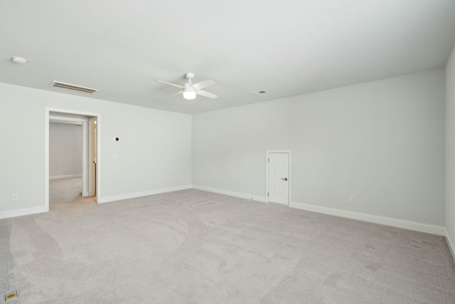 empty room featuring a ceiling fan, visible vents, light carpet, and baseboards