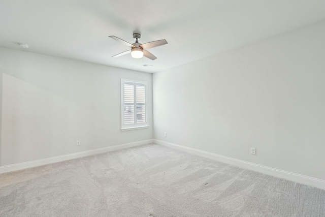 spare room featuring light carpet, ceiling fan, and baseboards