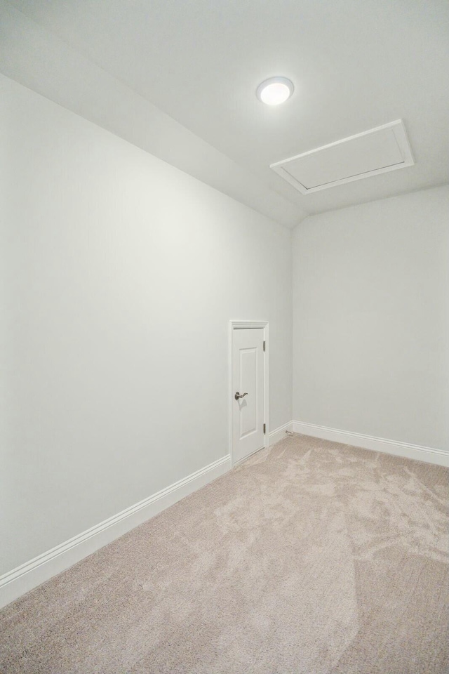 spare room featuring light carpet and baseboards