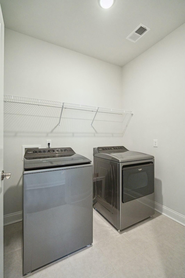 clothes washing area with laundry area, independent washer and dryer, visible vents, and baseboards