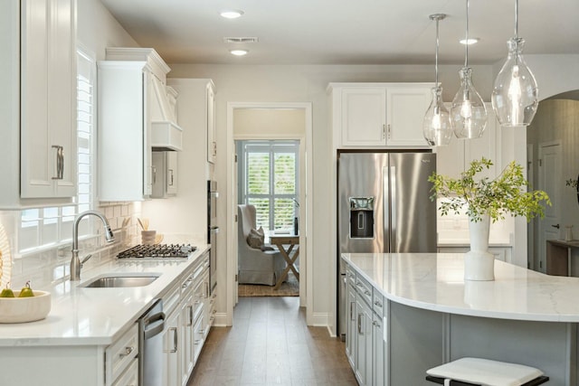 kitchen with decorative backsplash, dark wood-style flooring, stainless steel appliances, white cabinetry, and a sink