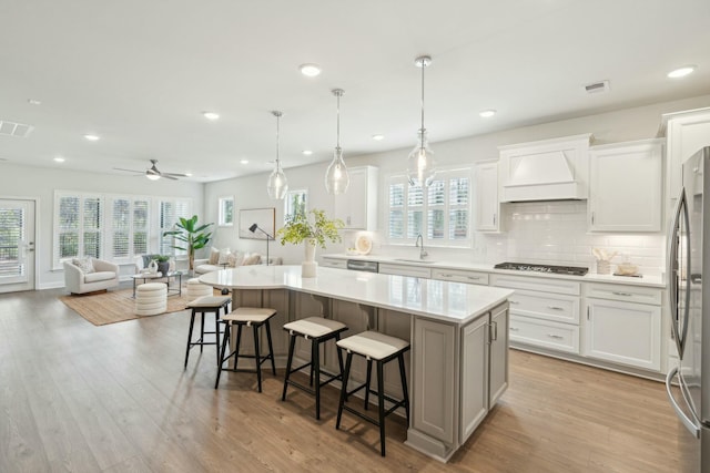 kitchen featuring stainless steel appliances, wood finished floors, open floor plan, custom exhaust hood, and a center island