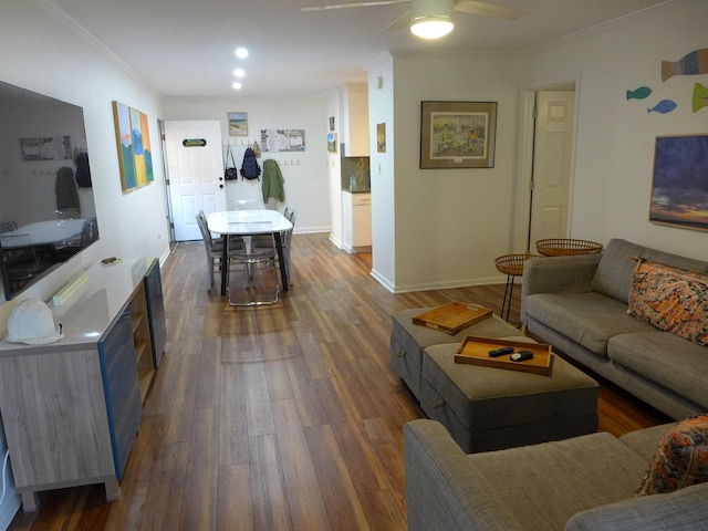 living room with dark wood-type flooring, ornamental molding, and ceiling fan