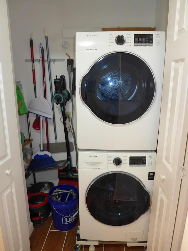 laundry room featuring dark wood-type flooring and stacked washer / dryer