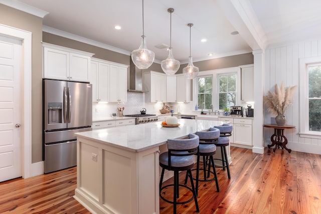 kitchen with appliances with stainless steel finishes, pendant lighting, white cabinetry, a center island, and light stone countertops