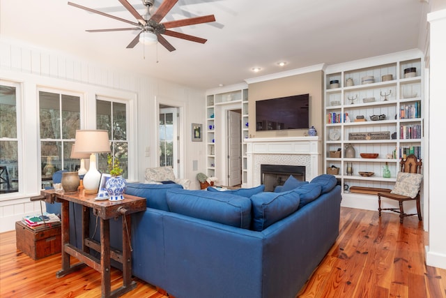 living room with a tiled fireplace, hardwood / wood-style flooring, and ceiling fan