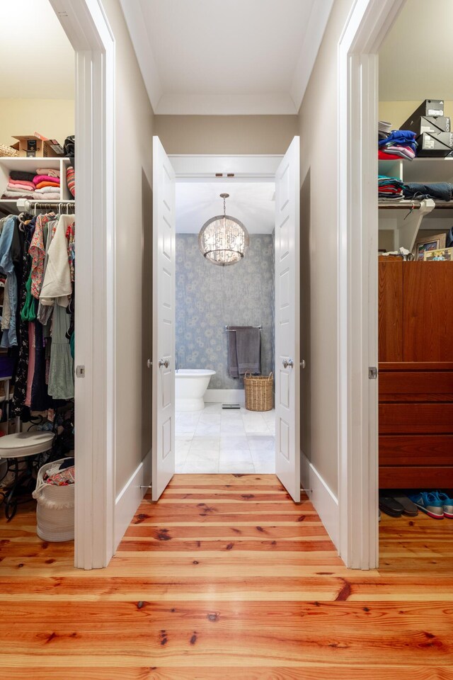 hall featuring crown molding, a notable chandelier, and light hardwood / wood-style flooring