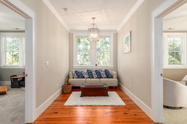 sitting room featuring crown molding, a notable chandelier, and light wood-type flooring