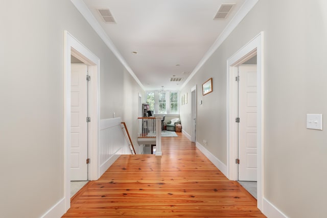 hallway featuring ornamental molding and light wood-type flooring