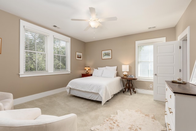 carpeted bedroom featuring multiple windows and ceiling fan