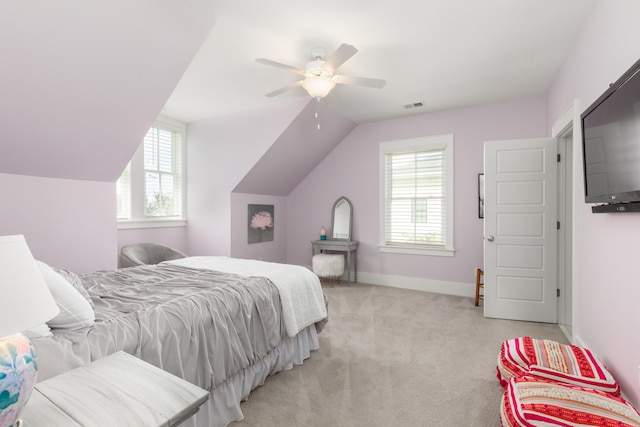 bedroom with multiple windows, vaulted ceiling, light colored carpet, and ceiling fan