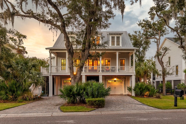 raised beach house featuring a yard, a garage, and a balcony