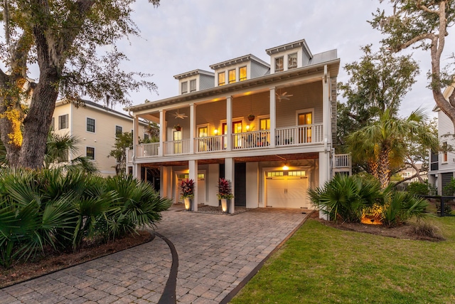 exterior space with a garage, a balcony, a front yard, and ceiling fan