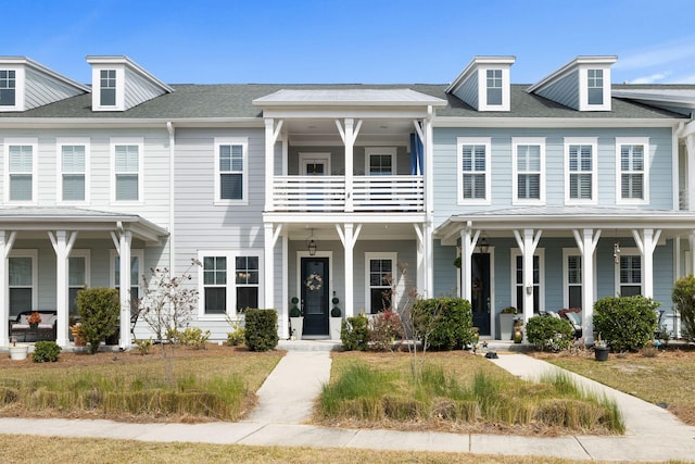 multi unit property with a balcony, a porch, and roof with shingles