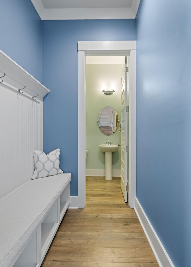 mudroom featuring a sink, light wood-style flooring, and baseboards