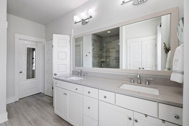 full bath featuring double vanity, a sink, and a shower stall