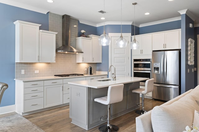 kitchen featuring visible vents, white cabinets, wall chimney exhaust hood, appliances with stainless steel finishes, and a sink