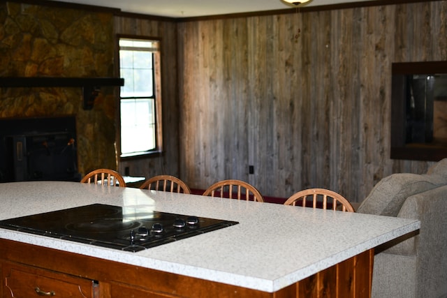 kitchen with a fireplace, black cooktop, and wooden walls