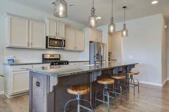 kitchen featuring hardwood / wood-style floors, appliances with stainless steel finishes, and an island with sink