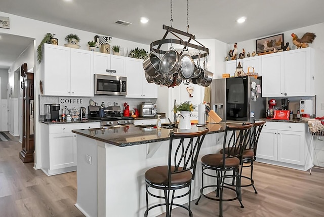 kitchen with tasteful backsplash, white cabinetry, appliances with stainless steel finishes, and a center island with sink