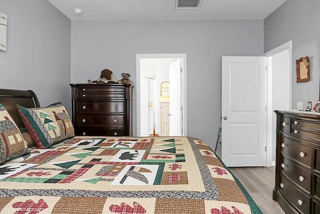 bedroom with ensuite bath and light hardwood / wood-style floors