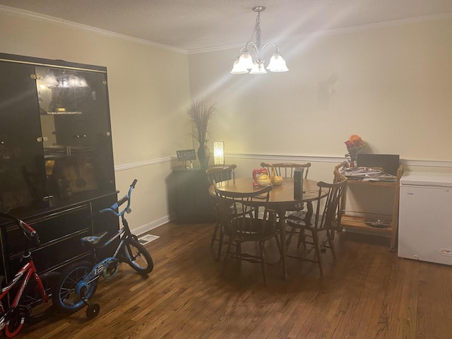 dining area featuring visible vents, hardwood / wood-style flooring, crown molding, baseboards, and a chandelier