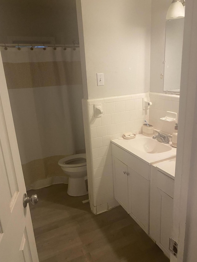 bathroom featuring vanity, wood finished floors, a wainscoted wall, tile walls, and toilet