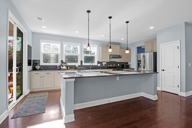 kitchen with tasteful backsplash, decorative light fixtures, a center island, dark stone countertops, and stainless steel appliances