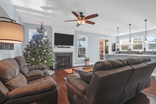 living room featuring dark wood-type flooring, a large fireplace, and ceiling fan