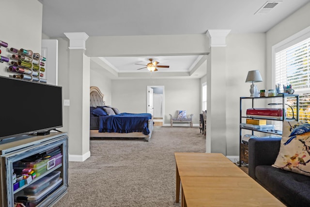 carpeted bedroom featuring decorative columns, ornamental molding, and a tray ceiling