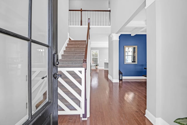 foyer featuring ornate columns, dark hardwood / wood-style flooring, and beamed ceiling