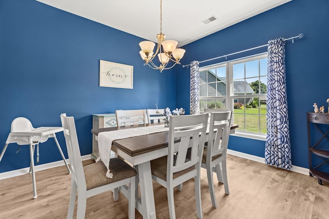 dining space with light wood-type flooring and a notable chandelier