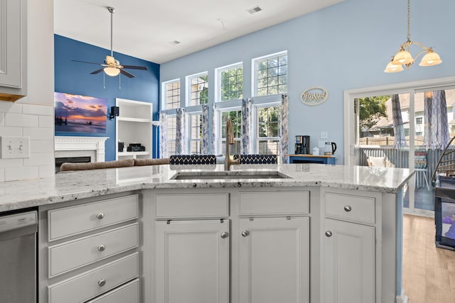 kitchen featuring dishwasher, sink, light hardwood / wood-style flooring, light stone countertops, and white cabinets