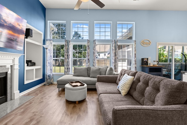 living room featuring ceiling fan, hardwood / wood-style floors, a wealth of natural light, and a premium fireplace