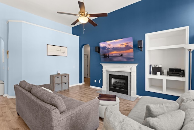 living room featuring ceiling fan, built in shelves, and light hardwood / wood-style flooring