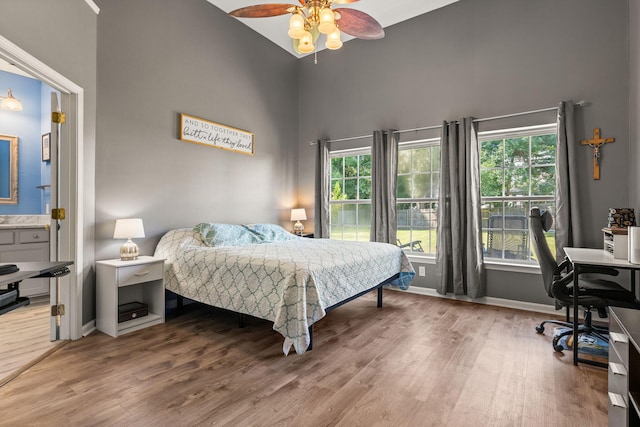 bedroom featuring ceiling fan, hardwood / wood-style flooring, and high vaulted ceiling