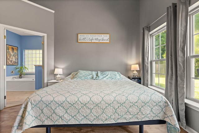 bedroom with multiple windows and hardwood / wood-style flooring