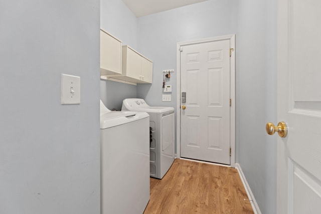 laundry room featuring cabinets, light hardwood / wood-style flooring, and washing machine and dryer