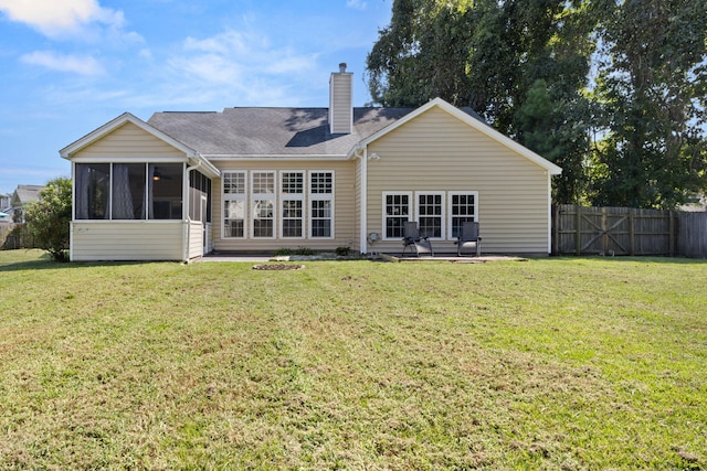 back of property featuring a lawn, a patio, and a sunroom