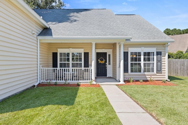 view of exterior entry with covered porch and a lawn