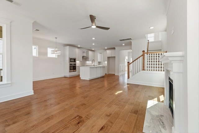 unfurnished living room featuring sink, ceiling fan, and light hardwood / wood-style flooring