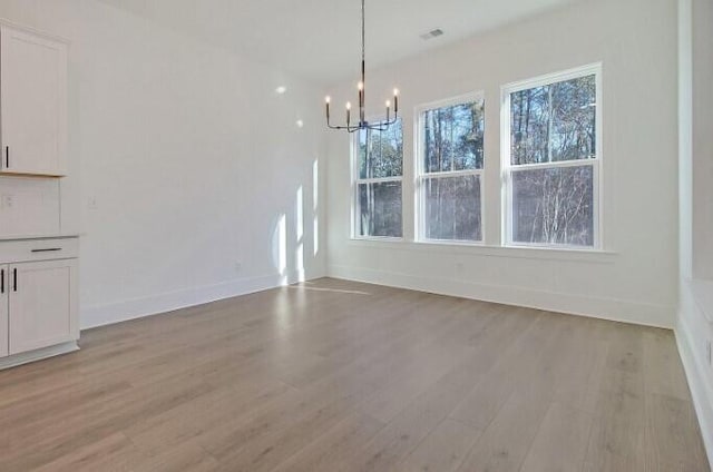 unfurnished dining area featuring a chandelier and light wood-type flooring