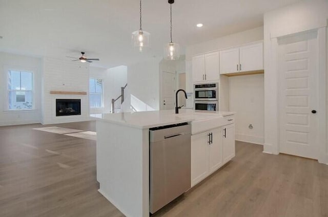 kitchen featuring a kitchen island with sink, white cabinetry, pendant lighting, and stainless steel appliances