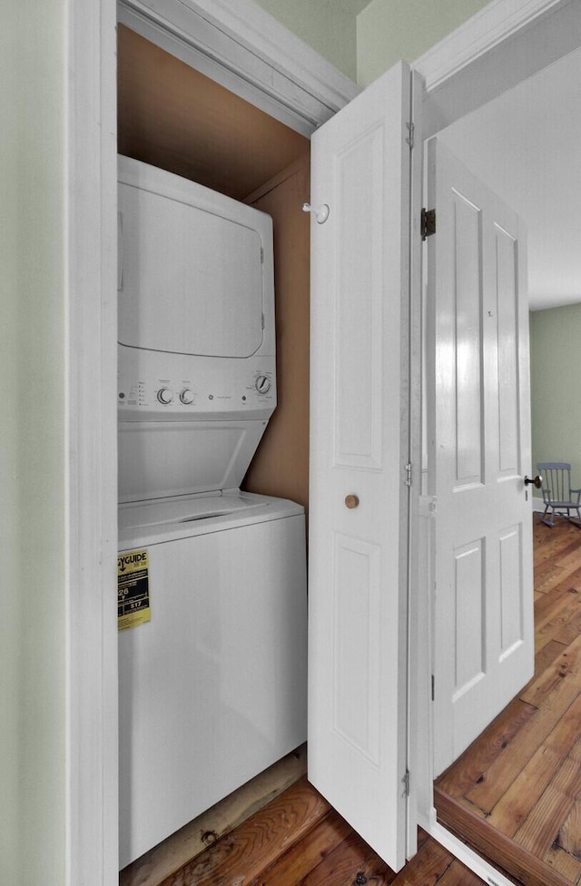 washroom with stacked washer / drying machine and wood-type flooring