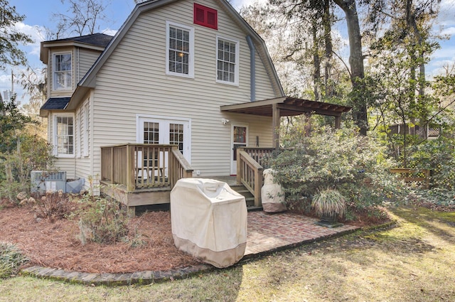 rear view of property with a wooden deck and a patio area