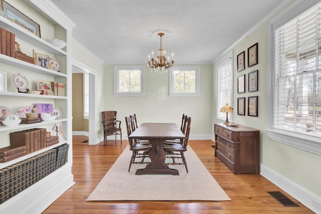 dining space featuring crown molding, a chandelier, and light wood-type flooring