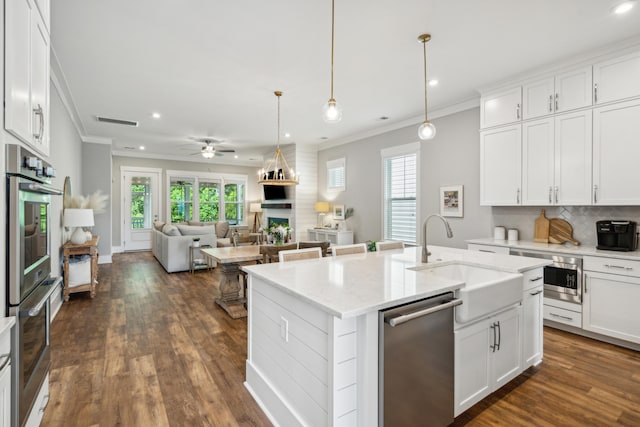 kitchen with white cabinets, appliances with stainless steel finishes, a kitchen island with sink, and sink