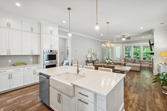 kitchen with ceiling fan, sink, hanging light fixtures, a kitchen island with sink, and white cabinets