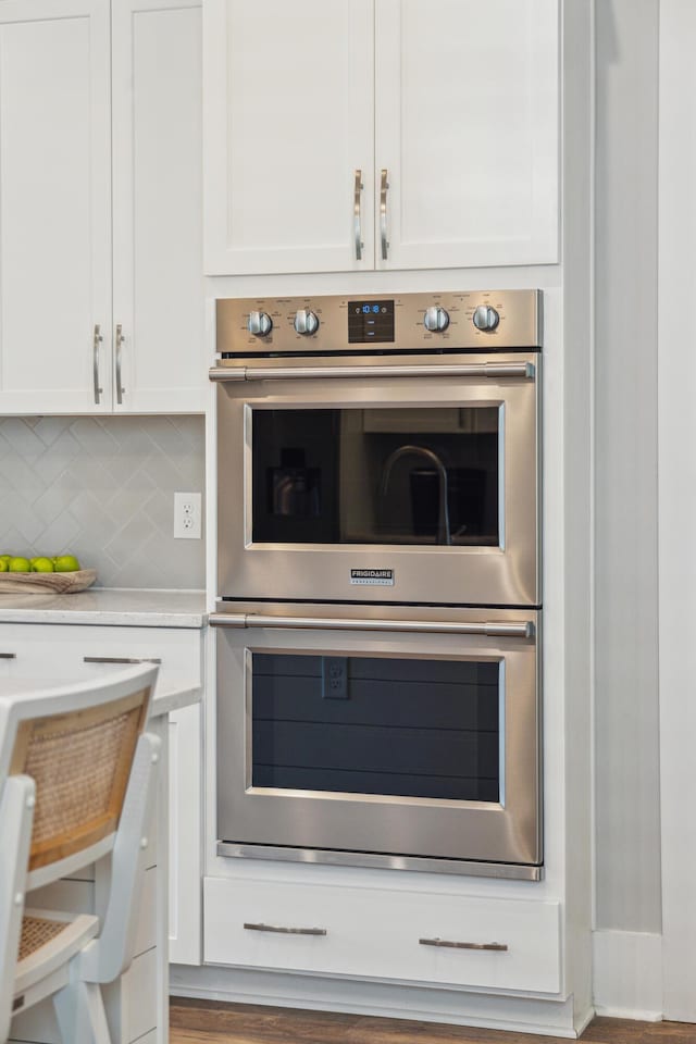 kitchen featuring decorative backsplash, white cabinetry, and stainless steel double oven